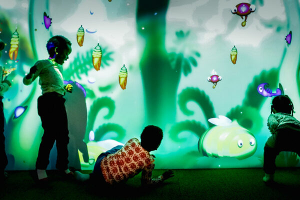 Barn som leker med den interaktive sanseveggen i lekeuniverset