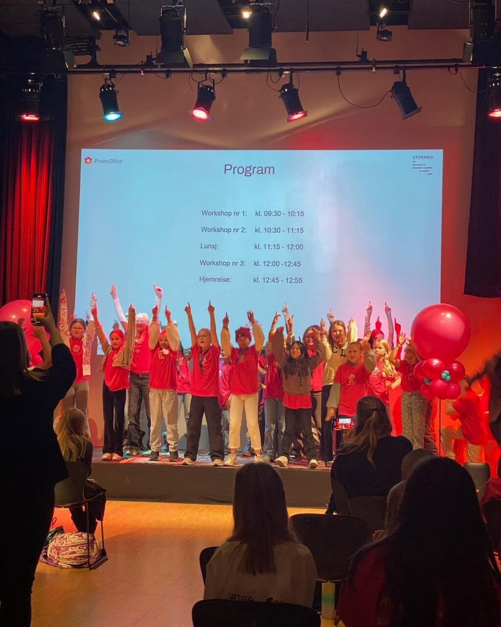 Deltakere på Girl Tech Fest står på scenen med hendene i været.