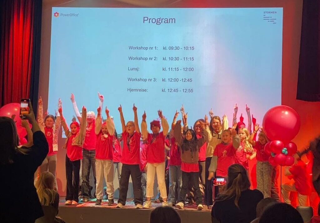 Deltakere på Girl Tech Fest står på scenen med hendene i været.
